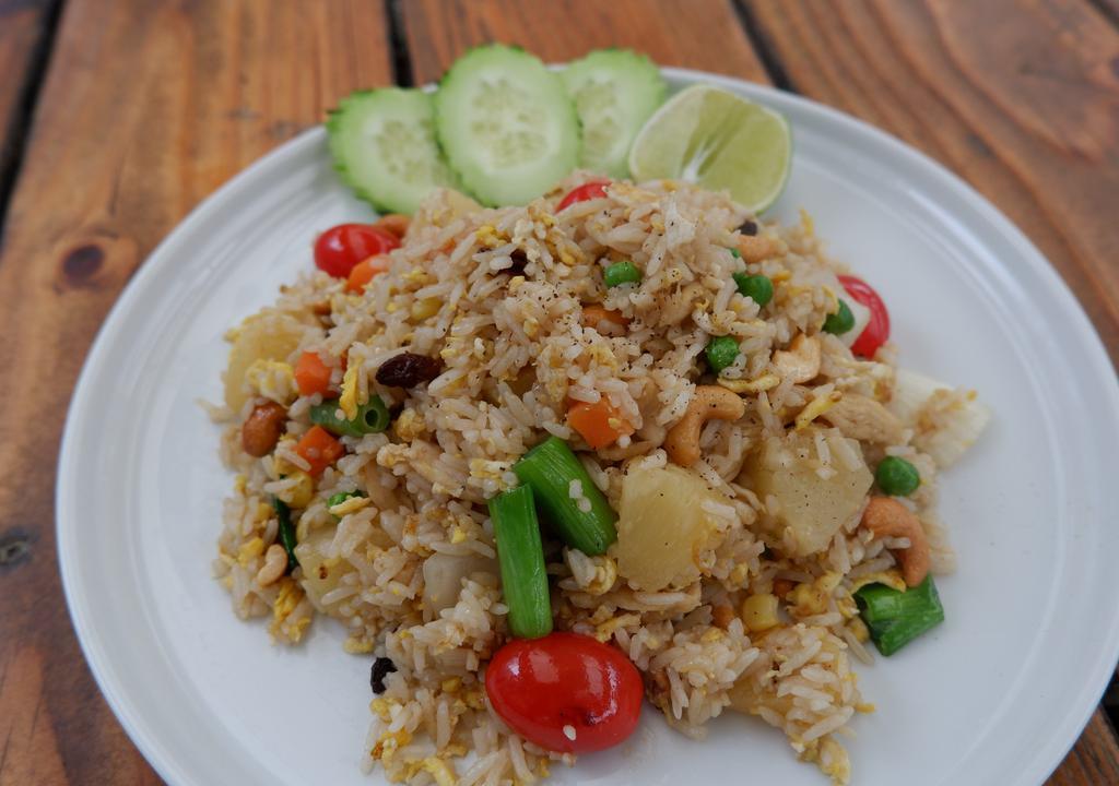 Pineapple Fried Rice · Fried rice with egg, raisins, onions, peas carrot, pineapple chunks, cashew nuts and tomatoes.
