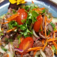 Thai Beef Salad · Pan-fired beef seasoned with onions, tomatoes, cucumber, scallion, and cilantro in spicy lim...