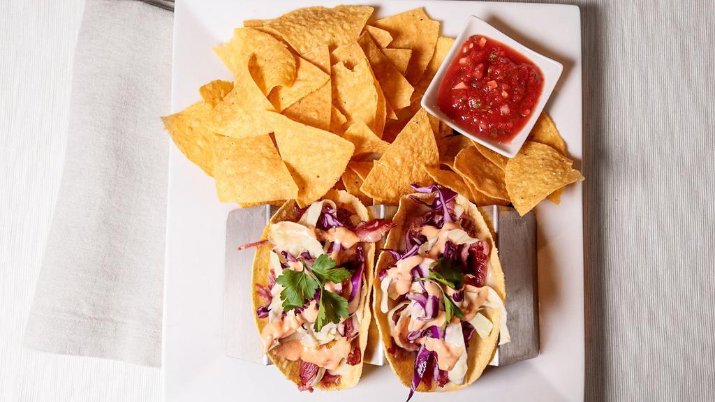 Corned Beef Taco · Slow roasted corned beef in a corn tortilla, swiss, cabbage, Russian dressing and a side of chips and salsa.