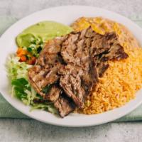 Carne Asada Plate · Two steaks with pico de gallo, lettuce, and guacamole on a plate with rice and beans.