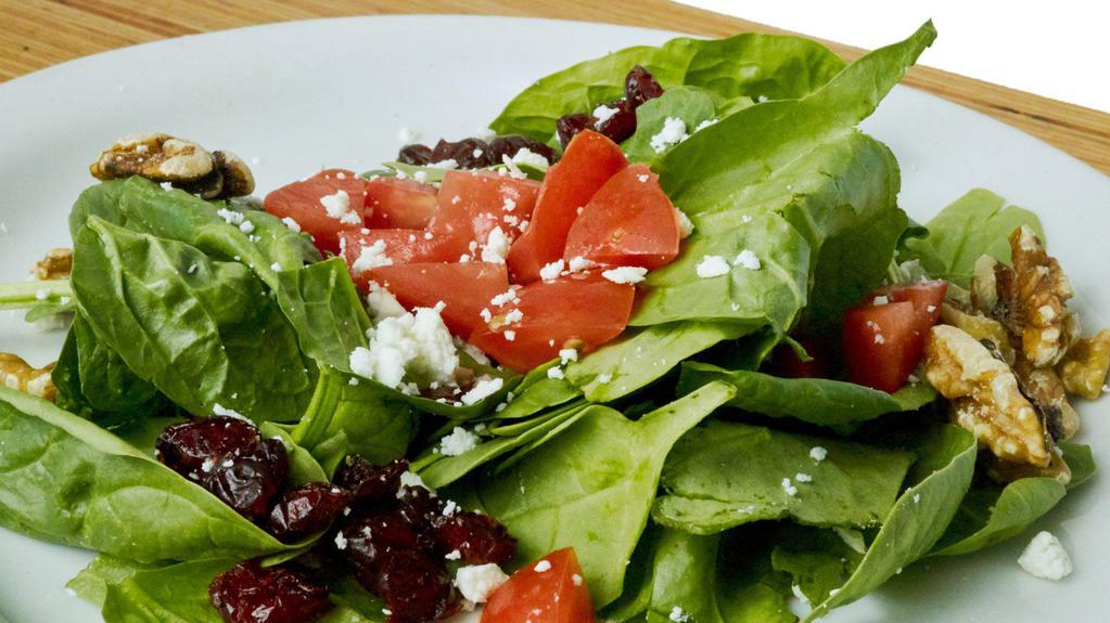 Spinach Salad · Fresh baby spinach topped with fresh tomato, walnuts, cranberry raisins, and feta, served with balsamic vinaigrette on the side.