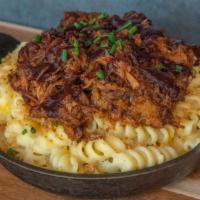 Pulled Pork Mac · House smoked pulled pork and blackberry ancho BBQ sauce on top of our house mac.