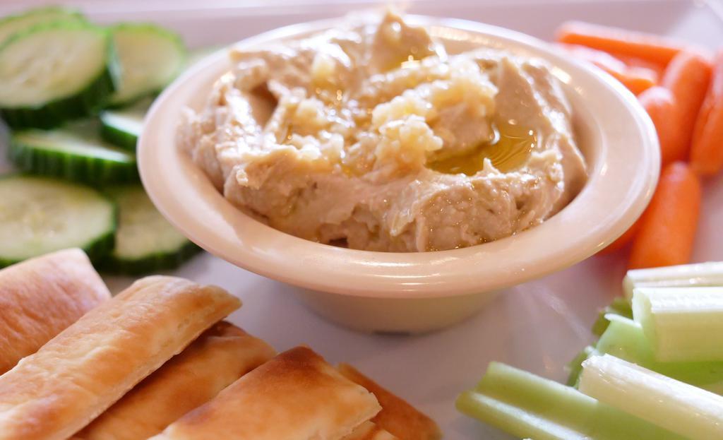 Hummus Plate · Fresh made red pepper and garlic hummus platter with cucumbers, carrots, celery and pita bread or gluten free cauliflower chips