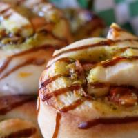 Pesto Wheels · Pesto, tomatoes, and onions rolled in pizza dough topped with balsamic glaze