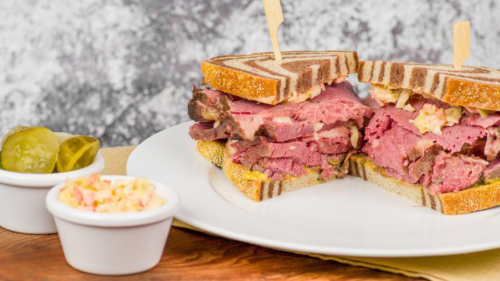 Corned Beef Ding · Hot corned beef sandwich ding size or Seattle style half the meat. Garnished with mustard, Russian, and coleslaw. Pickles and coleslaw on side. Sub potato salad for an additional charge. Rye, marble rye, gluten free, or sub a bagel for an additional charge.