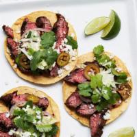 Grilled Steak Tostada Salad · Grilled steak layered with a small crispy corn tortilla, black beans, romaine lettuce, pico ...