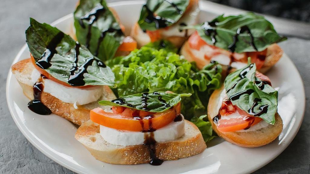 Caprese Bites · Slices of toasted baguette topped with fresh buffalo mozzarella, sliced tomato, fresh basil, and drizzled with balsamic glaze