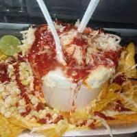 Chorriado · Corn in a cup on a plate of chips topped with cheese, mayonnaise, chile, and nacho cheese.