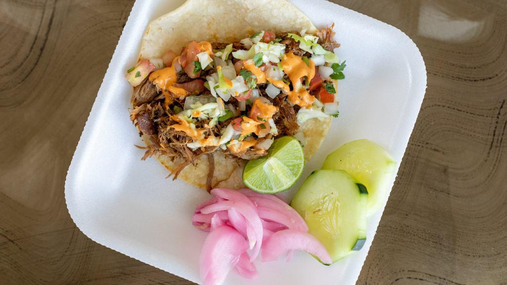 Puerco Con Chile Taco · Pork cooked low and slow with three types of chiles on a tortilla with pico cabbage and chipotle crema