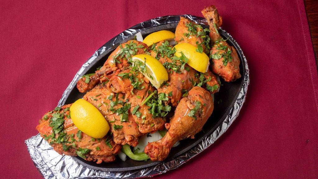 Tandoori Chicken · Marinated chicken cooked in its own juice in the tandoor. Marinated for 5-6 hours in yogurt, with a blend of flavorful spices, then prepared in the traditional Indian clay oven.