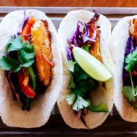 Fish Tacos · Three flour tortillas neatly filled with marinated fish and shredded cabbage. Garnished with...