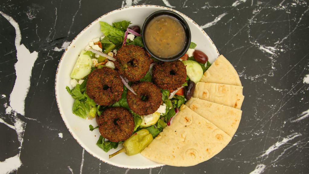 Falafel Greek Salad · Romaine lettuce, tomatoes, cucumbers, red onions, pitted black kalamata olives, and homemade vinaigrette dressing topped with Homemade falafels. Served with 1 pita bread.