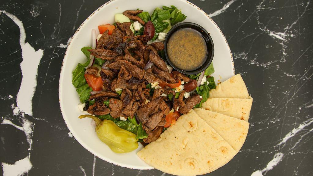 Beef Shawarma Greek Salad · Romaine lettuce, tomatoes, cucumbers, red onions, pitted black kalamata olives, and homemade vinaigrette dressing topped with beef shawarma. Served with 1 pita bread.