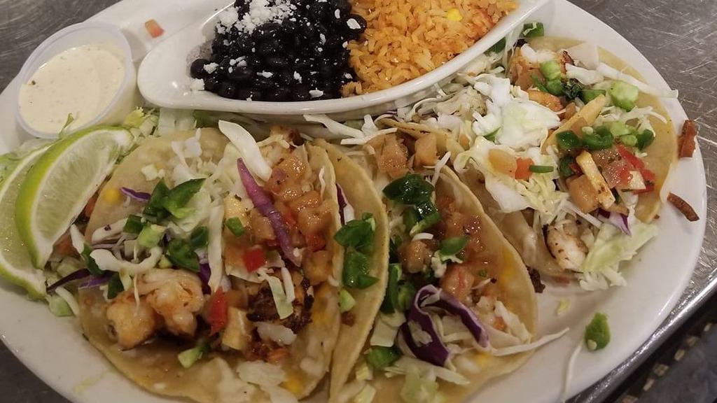 Shrimp Tacos · Three corn tortillas filled with grilled lime shrimp, topped with a pineapple chipotle slaw, cotija cheese and diced jalapeños. Served with black beans and rice.