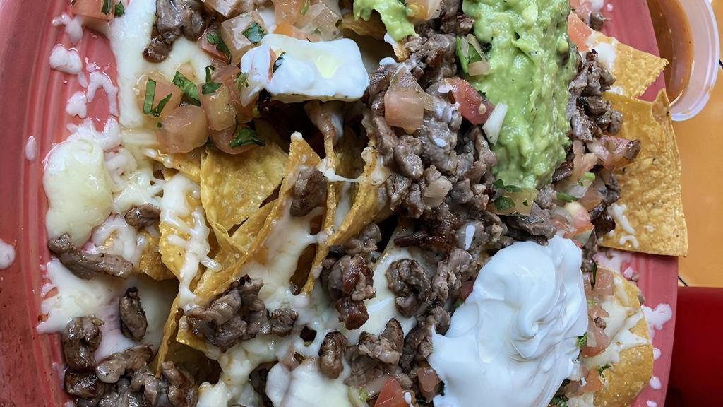 Super Nachos · Homemade corn chips with refried beans, our pico de gallo, Monterey jack cheese topped with guacamole and sour cream. Add your choice of meat.