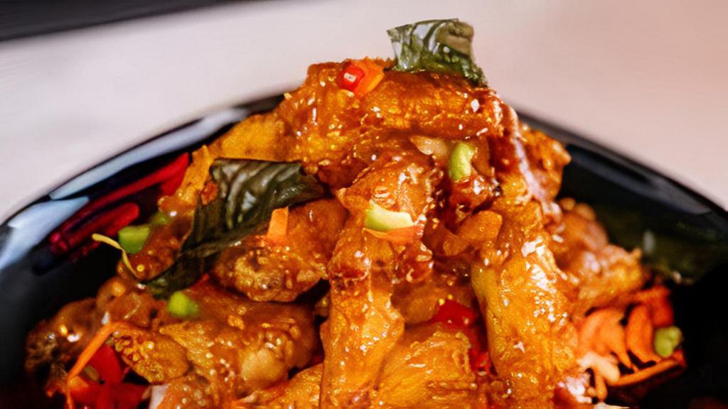 Crispy Garlic Chicken · Crispy chicken pieces stir-fried with a honey-infused mix of garlic and topped with crisped basil leaves garnished with chopped red bell peppers