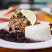 Lechon Asado · Slow roasted pork shoulder prepared with sauteed onions, served with moro rice, maduros & bl...