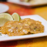 Tostones · Green plantains tossed in garlic mojo.