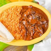 Pollo En Mole · Shredded chicken covered with mole sauce and onions, served with beans, rice, and two tortil...