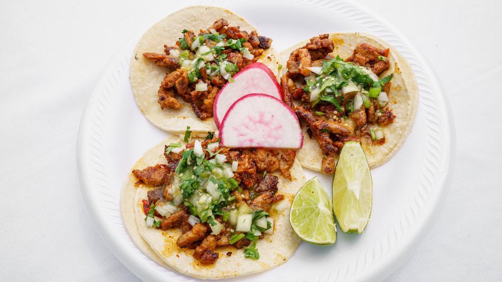 Tacos Al Pastor · Pork loin grilled in a special sauce and flame-broiled. Sliced folded into three soft corn tortillas with cilantro, and onions.