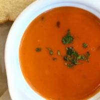 Tom Basil Bisque · Creamy tomato basil soup served with toast and a pickle.