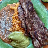 Carne Asada Plate · Two steaks with pico de gallo. lettuce, and guacamole on a plate with rice and beans.