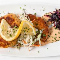 Indulgent Crab Cakes · Two indulgent lump crab cakes served over fresh coleslaw and cajun aioli, brought with a lem...