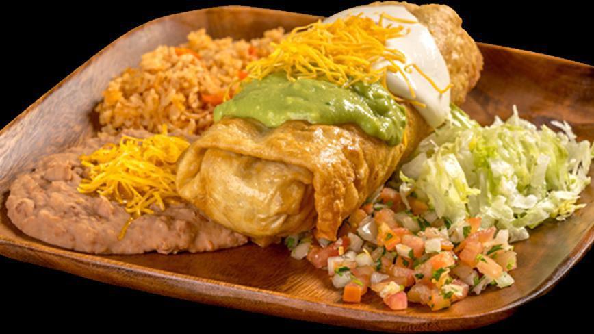 Chimichanga · Shredded beef chimichanga with bell peppers, tomatoes, and onions topped with guacamole and sour cream. With lettuce and pico de gallo on the plate.