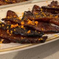 Candied Bacon · Decadent strips of brown sugar & pepper candied bacon.  Topped with orange zest.