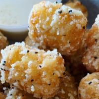 Truffle Tots · Crispy tots tossed in grated Parmesan cheese & truffle oil. Served with garlic crème.