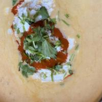 Hatch Green Chile Queso Dip · Homemade and finished with Cotija cheese, cilantro, and Valentina sauce.