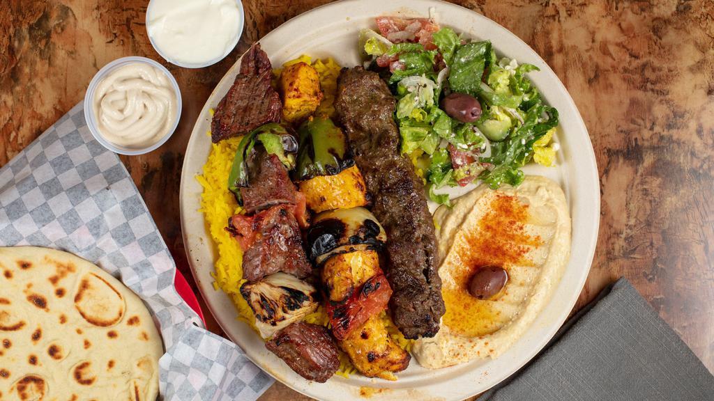 Mix Grill Plate · Three skewers of kababs: chicken, beef, and kafta, served with rice, hummus, Greek salad, pita bread, garlic and Tahini sauce.