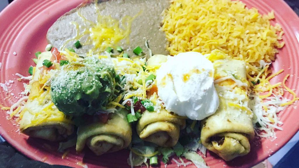 Flautas · Flour tortillas filled with spicy shredded beef, ground beef, or chicken, lettuce, tomatoes, and onions then rolled and fried until crispy. Served with rice, beans, guacamole, Parmesan cheese, and sour cream.