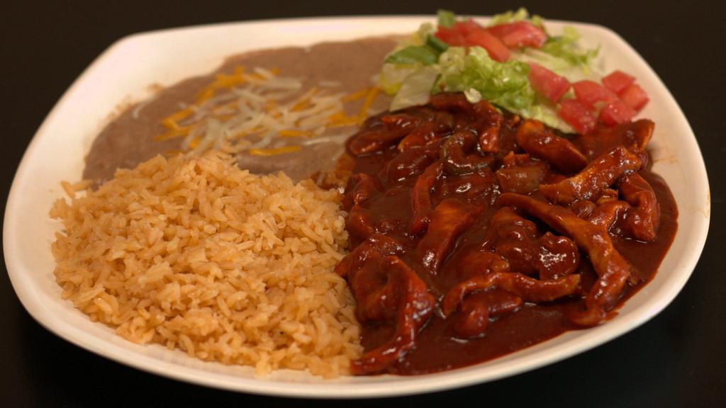 Pollo En Mole · Mole sauce, boneless chicken breast. Severed with rice, beans.