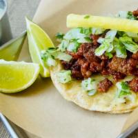 Al Pastor Taco · Tender pork shoulder marinated with guajillo, spices. Topped with pineapple, onions and cila...