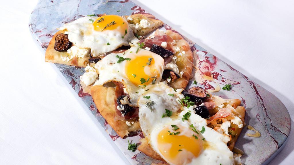 Egg, Prosciutto & Fig, Goat Cheese Pizza · A traditional flat bread topped with garlic chutney, sliced ripe figs, goat cheese, prosciutto and runny eggs. Drizzled with a honey and thyme mixture.