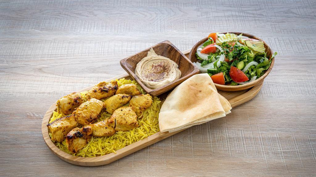 Chicken Tikka · Two skewers of grilled boneless chicken marinated in Food Land seasoning, served with rice, salad, and hummus.