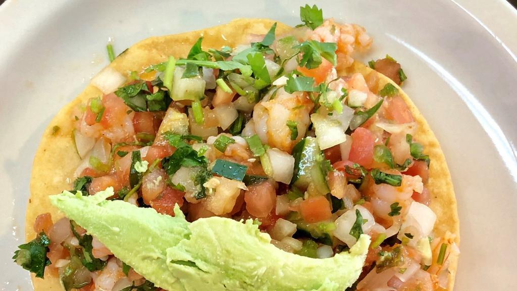 Ceviche Tostada · Prawns marinated in lime juice with pico de gallo and avocado sliced on top of a homemade corn tostada.