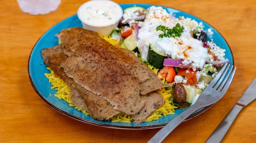 Lamb Shawarma Plate · Slow roasted lamb & beef shawarma slices drizzled with tahini sauce, served with a bed of basmati rice and Greek salad.