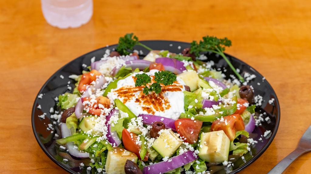 Greek Salad · A traditional Greek classic made with romaine lettuce, tomatoes, cucumbers, onions, kalamata olives topped with feta cheese, and our in-house dressing and tzatziki sauce.