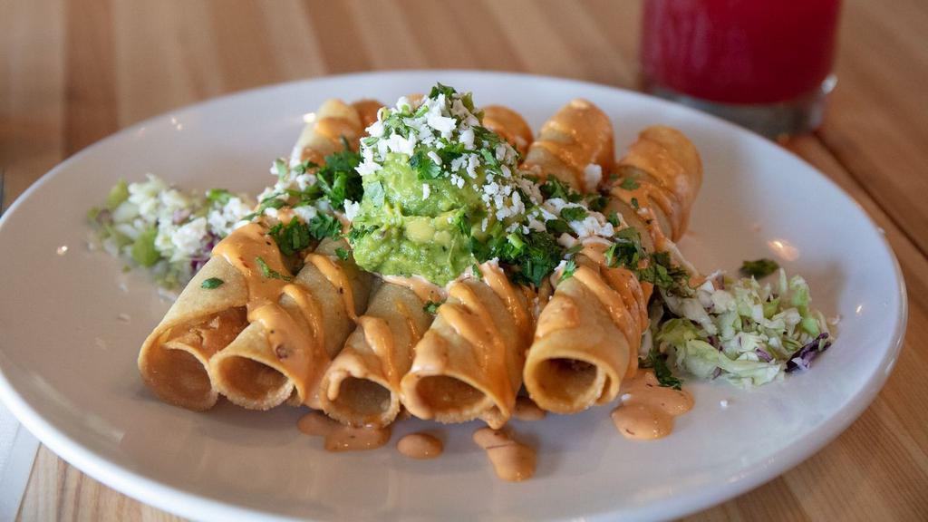 Taquitos · Five crispy rolled tacos stuffed with shredded chicken, topped with guacamole, cilantro, queso fresco, seis-style chipotle crema.