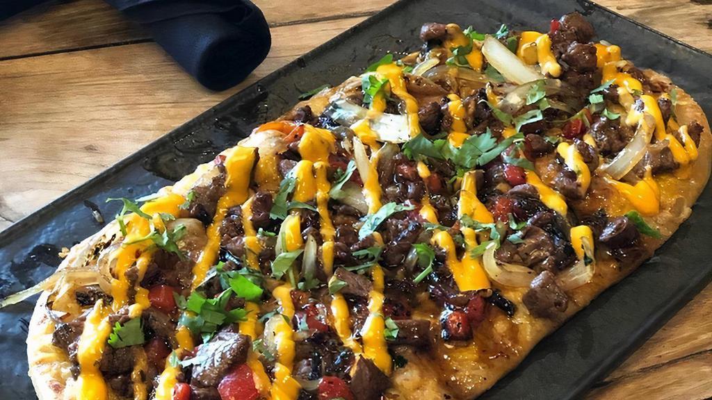Louie'S Steak Flatbread · sliced flat iron steak, roasted red peppers, onions, cilantro, cheddar-jack cheese, spicy aioli