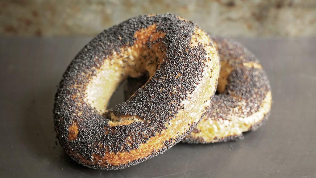Poppy Seed Bagel · Our organic naturally-leavened bagels are hand-rolled, given a long ferment, and have just a hint of rye, which adds to their depth of flavor. The caramelized crust has a glossy sheen and the airy interior has a tight, springy crumb that balances the mild tang of sourdough with just enough malty sweetness. Topped with poppy seeds.