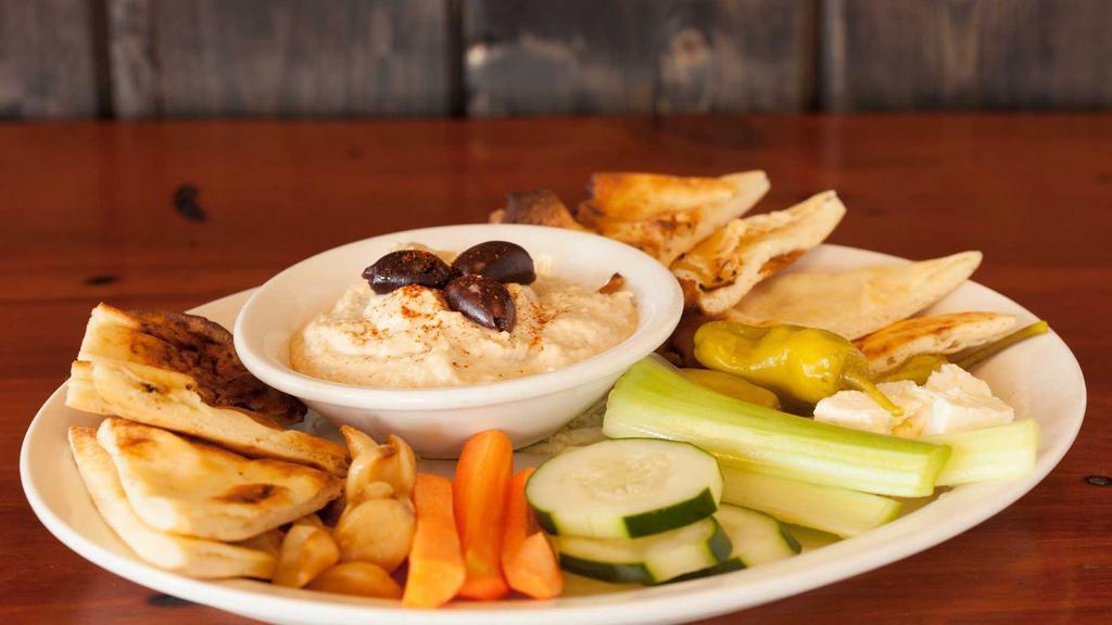 Hummus Plate · Freshly made hummus served with toasted naan, roasted garlic, feta cheese, kalamata olives, celery, cucumbers, pickled onions, carrot sticks and pepperoncinis.