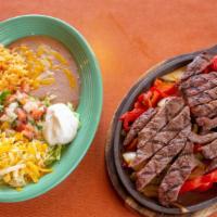 Carne Asada Fajitas · Carne asada marinated in our secret sauce, delivered sizzling hot over a bed of sauteed onio...