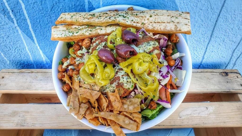 Vegan Doner Salad · Romain, cabbage, carrot, onion, green pepper, cucumber, olives, pepperoncinis, tomato, fried lavash chips, crispy garbanzo, fried pita, lemon-herb tahini and a side of balsamic dressing.