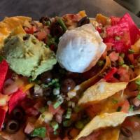 Deluxe Nachos · Ground beef, black olives, jalapeños, onions, tomatoes, sour cream and guacamole. Accompanie...