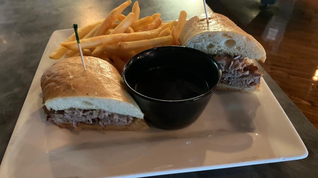 Prime Rib Dip Sandwich · Sliced Prime rib piled high on a fresh baguette bun. Served with au jus for dipping’ and fries.
