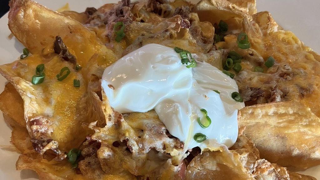 Expolding Cheddar Potatoes · Thin-sliced HUB chips topped with melted cheese, green onions, crispy bacon & sour cream