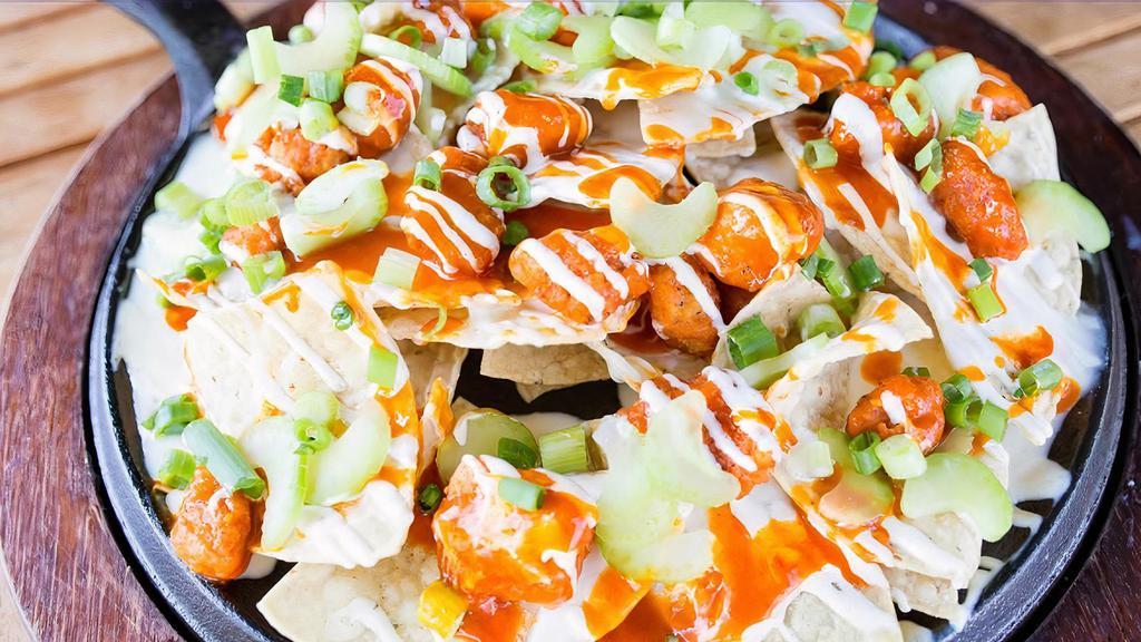 Buffalo Hot Nacho · Popcorn chicken breast tossed in buffalo hot sauce, white queso, ranch dressing, celery, and green onions on top of our housemade corn chips.